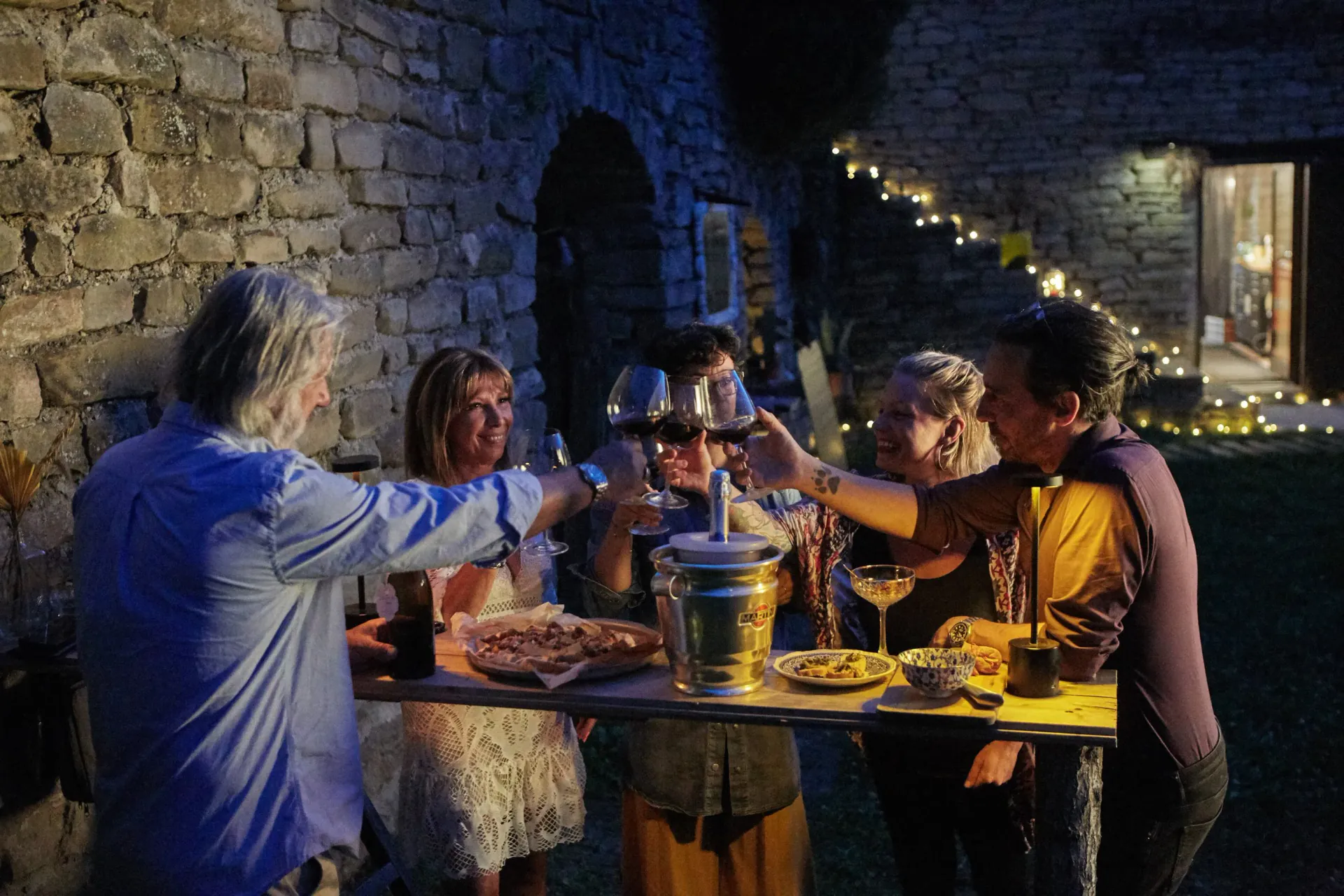 A woman relaxing on a striped hammock tied between two trees in a lush green outdoor setting, with a scenic view of hills and dense forest in the background