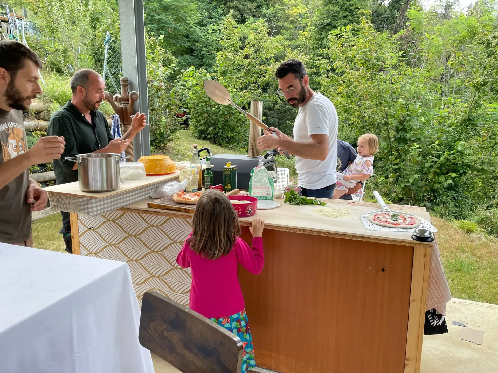 Group of people celebrating with wine outside at night, raising glasses in a toast, in front of a rustic stone wall decorated with string lights